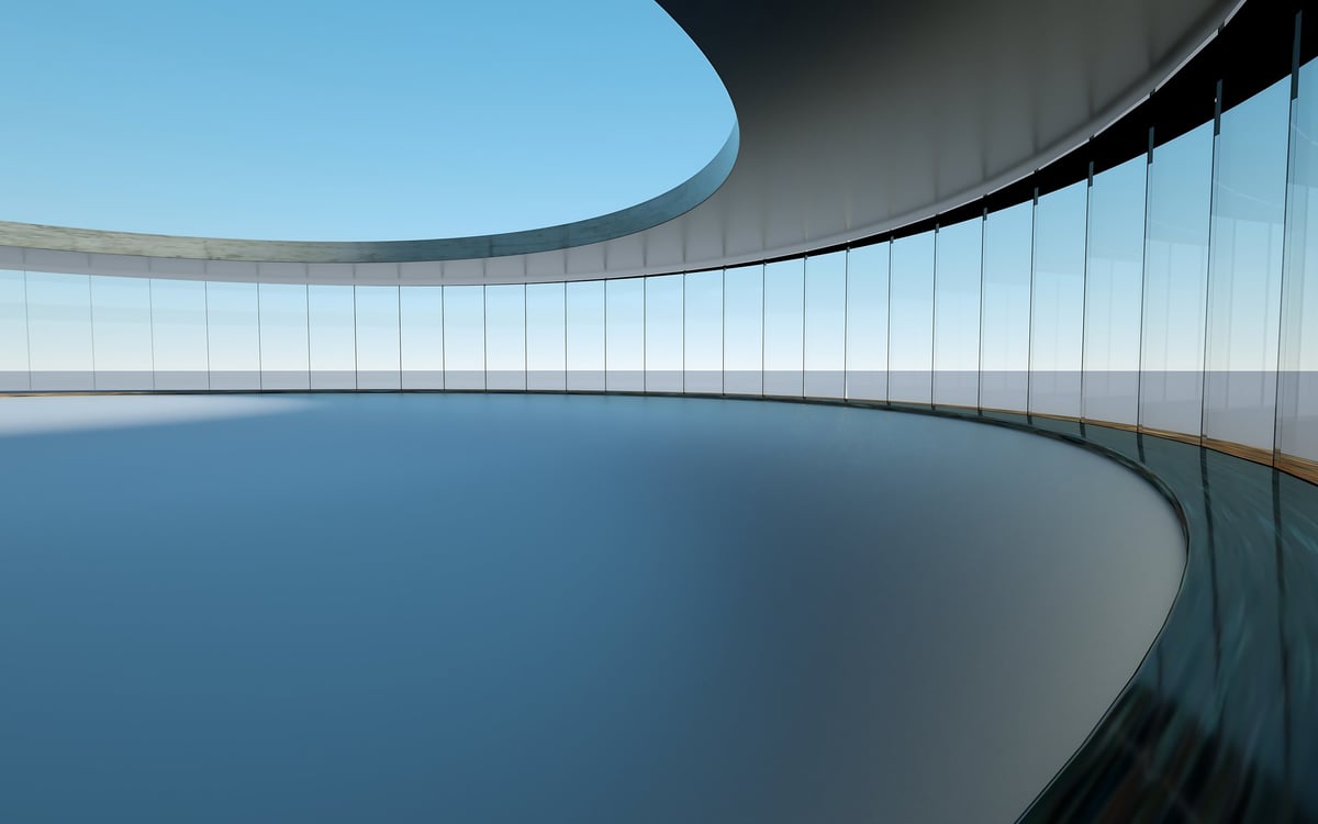 Sala curva de doble altura con ventanales de piso a techo